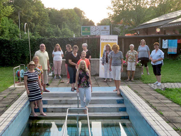 13 Mitglieder des Fördervereins stehen am Pool einer Kneipp Anlage, die von grüner Wiese und einer grünen Hecke umgeben ist.